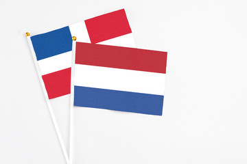 Netherlands and Dominican Republic stick flags on white background. High quality fabric, miniature national flag. Peaceful global concept.White floor for copy space.