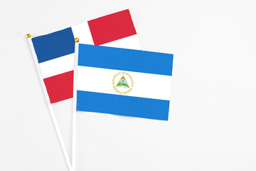 Nicaragua and Dominican Republic stick flags on white background. High quality fabric, miniature...