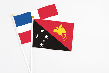 Papua New Guinea and Dominican Republic stick flags on white background. High quality fabric, miniature national flag. Peaceful global concept.White floor for copy space.