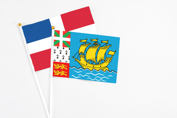 Saint Pierre And Miquelon and Dominican Republic stick flags on white background. High quality fabric, miniature national flag. Peaceful global concept.White floor for copy space.