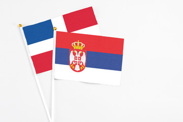 Serbia and Dominican Republic stick flags on white background. High quality fabric, miniature national flag. Peaceful global concept.White floor for copy space.