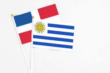 Uruguay and Dominican Republic stick flags on white background. High quality fabric, miniature national flag. Peaceful global concept.White floor for copy space.