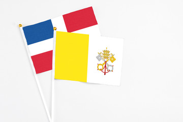 Vatican City and Dominican Republic stick flags on white background. High quality fabric, miniature national flag. Peaceful global concept.White floor for copy space.