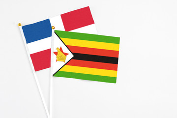 Zimbabwe and Dominican Republic stick flags on white background. High quality fabric, miniature national flag. Peaceful global concept.White floor for copy space.