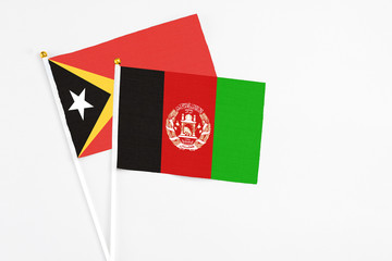 Afghanistan and East Timor stick flags on white background. High quality fabric, miniature national flag. Peaceful global concept.White floor for copy space.