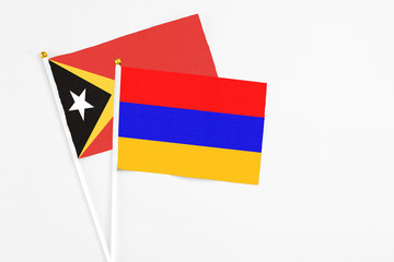 Armenia and East Timor stick flags on white background. High quality fabric, miniature national flag. Peaceful global concept.White floor for copy space.