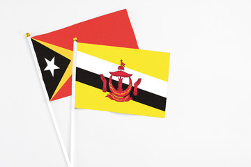 Brunei and East Timor stick flags on white background. High quality fabric, miniature national flag. Peaceful global concept.White floor for copy space.