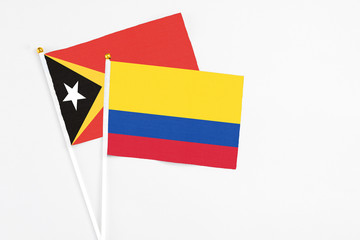 Colombia and East Timor stick flags on white background. High quality fabric, miniature national flag. Peaceful global concept.White floor for copy space.