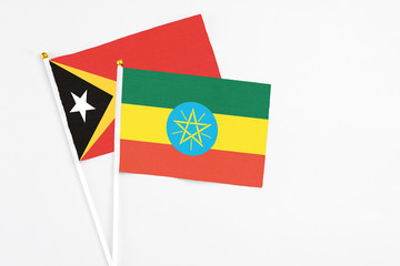 Ethiopia and East Timor stick flags on white background. High quality fabric, miniature national flag. Peaceful global concept.White floor for copy space.