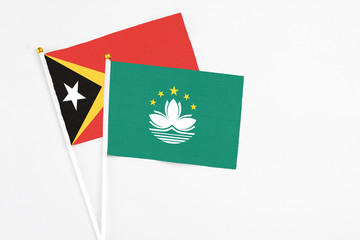 Macao and East Timor stick flags on white background. High quality fabric, miniature national flag. Peaceful global concept.White floor for copy space.