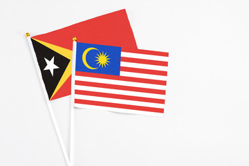 Malaysia and East Timor stick flags on white background. High quality fabric, miniature national flag. Peaceful global concept.White floor for copy space.