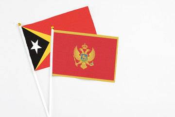 Montenegro and East Timor stick flags on white background. High quality fabric, miniature national flag. Peaceful global concept.White floor for copy space.