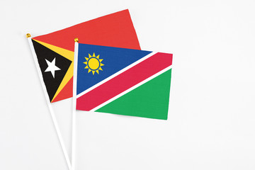 Namibia and East Timor stick flags on white background. High quality fabric, miniature national flag. Peaceful global concept.White floor for copy space.