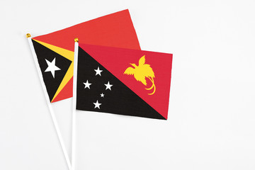Papua New Guinea and East Timor stick flags on white background. High quality fabric, miniature national flag. Peaceful global concept.White floor for copy space.