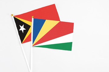 Seychelles and East Timor stick flags on white background. High quality fabric, miniature national flag. Peaceful global concept.White floor for copy space.