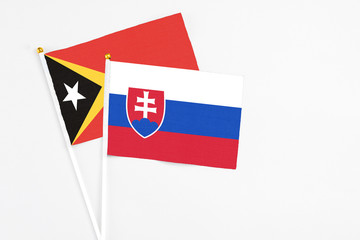 Slovakia and East Timor stick flags on white background. High quality fabric, miniature national flag. Peaceful global concept.White floor for copy space.