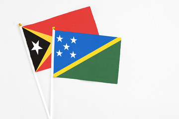 Solomon Islands and East Timor stick flags on white background. High quality fabric, miniature national flag. Peaceful global concept.White floor for copy space.