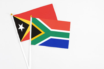 South Africa and East Timor stick flags on white background. High quality fabric, miniature national flag. Peaceful global concept.White floor for copy space.
