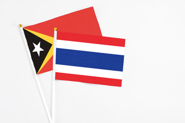 Thailand and East Timor stick flags on white background. High quality fabric, miniature national flag. Peaceful global concept.White floor for copy space.