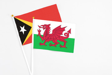 Wales and East Timor stick flags on white background. High quality fabric, miniature national flag. Peaceful global concept.White floor for copy space.