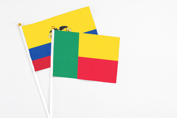 Benin and Ecuador stick flags on white background. High quality fabric, miniature national flag. Peaceful global concept.White floor for copy space.