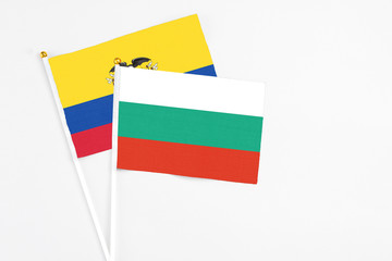 Bulgaria and Ecuador stick flags on white background. High quality fabric, miniature national flag. Peaceful global concept.White floor for copy space.