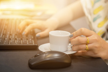 Woman hand holdding coffee cup with working table