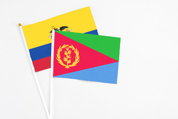 Eritrea and Ecuador stick flags on white background. High quality fabric, miniature national flag. Peaceful global concept.White floor for copy space.