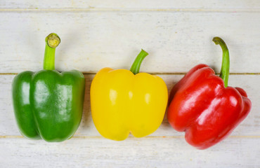 Colorful green , red and yellow peppers paprika on wood background - bell pepper