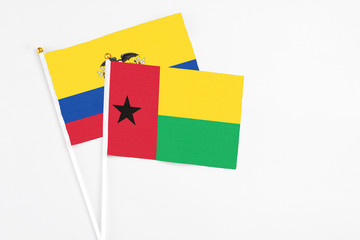 Guinea Bissau and Ecuador stick flags on white background. High quality fabric, miniature national flag. Peaceful global concept.White floor for copy space.