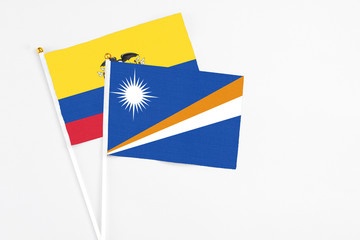 Marshall Islands and Ecuador stick flags on white background. High quality fabric, miniature national flag. Peaceful global concept.White floor for copy space.