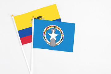 Northern Mariana Islands and Ecuador stick flags on white background. High quality fabric, miniature national flag. Peaceful global concept.White floor for copy space.