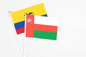 Oman and Ecuador stick flags on white background. High quality fabric, miniature national flag. Peaceful global concept.White floor for copy space.