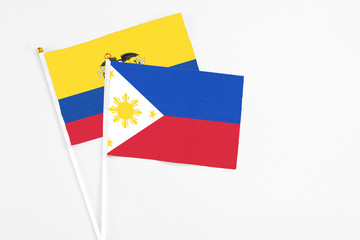 Philippines and Ecuador stick flags on white background. High quality fabric, miniature national flag. Peaceful global concept.White floor for copy space.