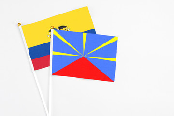 Reunion and Ecuador stick flags on white background. High quality fabric, miniature national flag. Peaceful global concept.White floor for copy space.