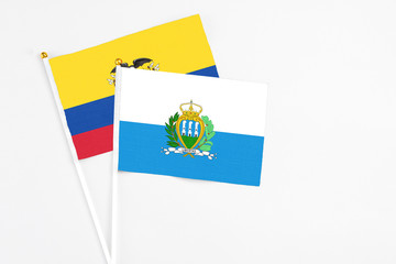 San Marino and Ecuador stick flags on white background. High quality fabric, miniature national flag. Peaceful global concept.White floor for copy space.