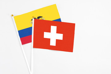 Switzerland and Ecuador stick flags on white background. High quality fabric, miniature national flag. Peaceful global concept.White floor for copy space.