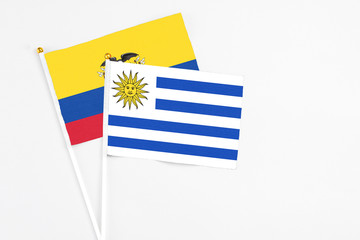 Uruguay and Ecuador stick flags on white background. High quality fabric, miniature national flag. Peaceful global concept.White floor for copy space.