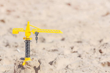 Toy yellow building crane on the sand