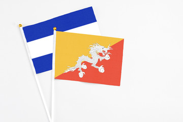 Bhutan and El Salvador stick flags on white background. High quality fabric, miniature national flag. Peaceful global concept.White floor for copy space.