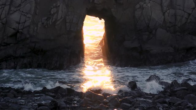 Epic sunlight shines as godly rays pierce the stone making way for awesome and amazing light in this religious type metaphoric scene in the Pacific Ocean.
