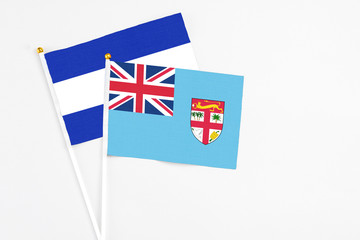 Fototapeta premium Fiji and El Salvador stick flags on white background. High quality fabric, miniature national flag. Peaceful global concept.White floor for copy space.