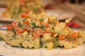 Russian salad on a white plate on a festive table