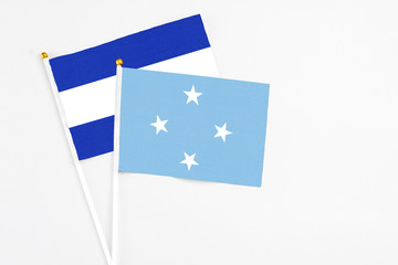 Micronesia and El Salvador stick flags on white background. High quality fabric, miniature national flag. Peaceful global concept.White floor for copy space.