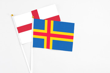 Aland Islands and England stick flags on white background. High quality fabric, miniature national flag. Peaceful global concept.White floor for copy space.