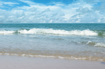 Soft waves of blue sea on sandy beach for the background.