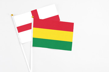 Bolivia and England stick flags on white background. High quality fabric, miniature national flag. Peaceful global concept.White floor for copy space.