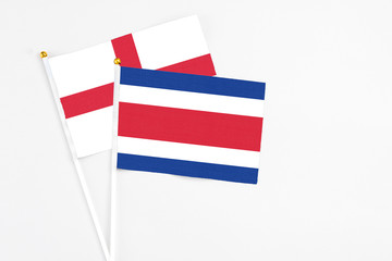 Costa Rica and England stick flags on white background. High quality fabric, miniature national flag. Peaceful global concept.White floor for copy space.