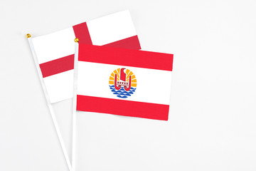 French Polynesia and England stick flags on white background. High quality fabric, miniature national flag. Peaceful global concept.White floor for copy space.