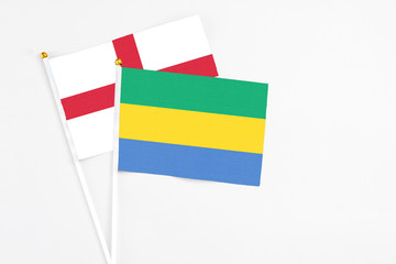 Gabon and England stick flags on white background. High quality fabric, miniature national flag. Peaceful global concept.White floor for copy space.